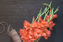 Orange Gladiolus On Tinted Black Background, Top View. Floral Rope For Bouquets On Wooden Table. Flat Lay. Nature Concept. A Place For Your Inscription. Background For Site Design, Landing Or Blog.