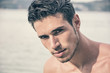 © theartofphoto - Attractive young man in the sea getting out of water with wet hair, looking in camera