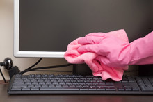 Hand In Rubber Protective Glove With Dry Microfiber Cloth Carefully Wiping Computer Screen From Dust. Regular Clean Up.