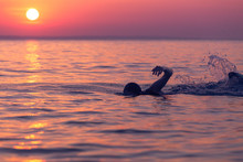 Swimmer At Sunset Over Sea
