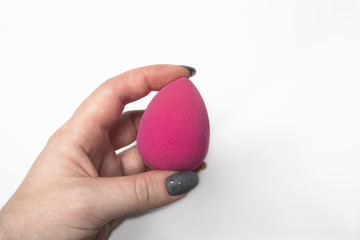 Woman's hand holding pink beauty blender over a white background