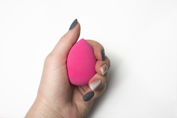 Sticker - Female hand holding pink beauty blender over a white background