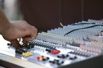 A sound mixer with the operator's hand changing the potentiometer setting