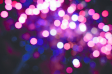 Abstract pink purple colored out of focus blurry party lights in the background at night.