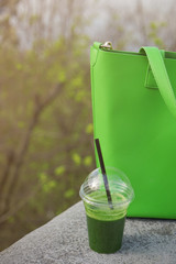 Fototapete - Cup of fresh vegetable smoothie and  green bag on street