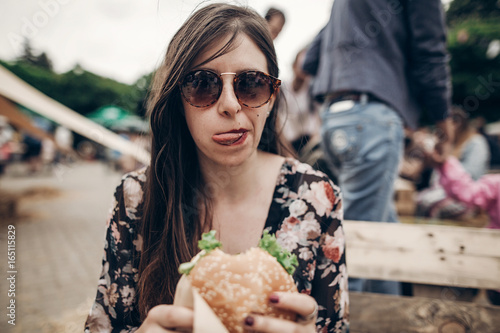 Fotografie, Obraz stylish hipster woman eating juicy burger