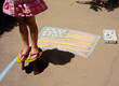 © Carolyn Lagattuta/Stocksy - Little girl standing on a bench above a chalk flag for Memorial Day