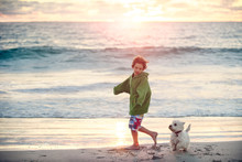 Boy Running With His Dog At Beach At Sunset