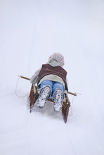 A Young Girl Sleds Down A Slope On An Old Wooden Sled