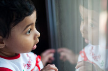 Baby Girl Looking Amazed At Her Reflection On A Window Glass