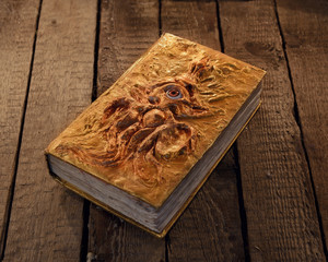 Close up of magic book with golden cover and marine monster image. Mystic Halloween still life 