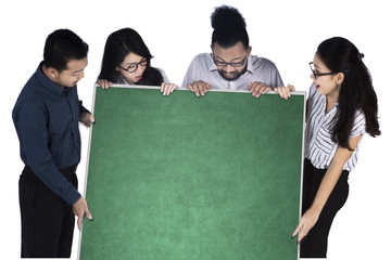 Wall Mural - Cheerful business team holds empty chalkboard