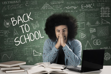 Wall Mural - Sad male student with scribble in class