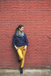 © BONNINSTUDIO/Stocksy - Beautiful woman standing in front red brick wall.