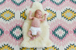 © Meaghan Curry Photography/Stocksy - newborn laying on a sheepskin and a patterned rug