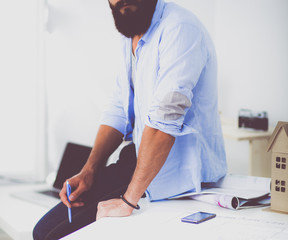 Wall Mural - Portrait of male designer in hat with blueprints at desk 