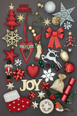 Symbols of christmas with glitter joy sign, new and old fashioned bauble decorations, holly, mistletoe, mince pie and fir on grey background.