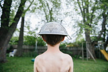 Boy Wearing Colander On His Head Looks Out Into His Backyard