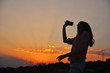 © Ivan - Silhouette of Young Attractive Hipster Girl Listening Music On The Mobile Phone And Dance At Sunset