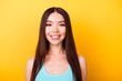 © deagreez - Close up portrait of young charming asian lady, standing on the yellow background and smiling, wearing casual blue singlet