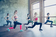 © deagreez - Five young fashionable sportswomen are stretching their legs by doing squats, so bendy and flexible, wearing trendy sport outfit, shoes, training in the modern studio
