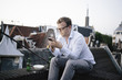 © Ivo de Bruijn/Stocksy - Young businessman at his rooftop looking at his cellphone