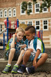 © aaronbelford inc/Stocksy - Two boys sharing headset while looking at smartphone