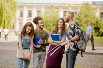 College friends standing, laughing in campus. Young people having fun in the university park.