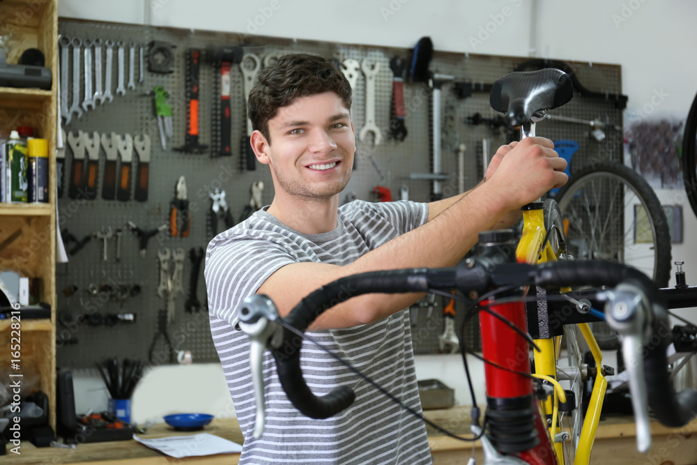 Young man working in bicycle repair shop