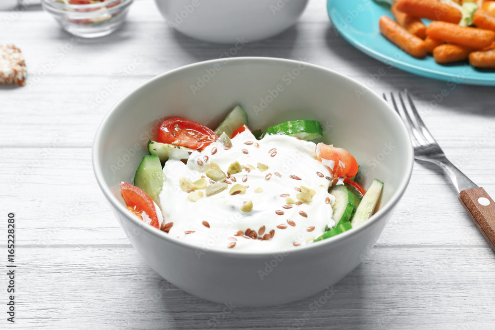Fresh salad with yogurt on table