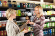 Young woman and assistant choosing perfume at store