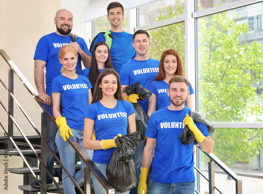 Young volunteers with garbage bags on staircase