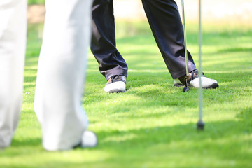 Wall Mural - Legs of young men playing golf on course in sunny day