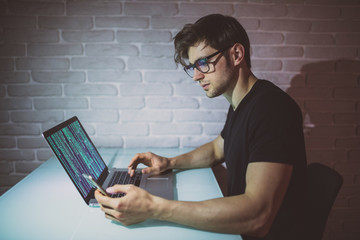 handsome young programer work in night with software and also use the phone