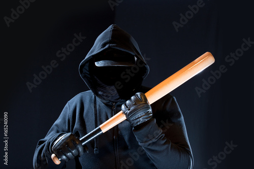 Photo  ein maskierter Mann mit Kapuze hält einen Baseballschläger in seinen Händen