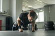 © lenblr - Sportsman wearing black shorts and t-shirt doing push-ups on fists in gym.