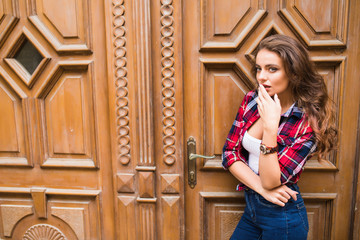 Wall Mural - portrait of cute smiling woman on a background of braun vintage door wearing casual clothes in summer city