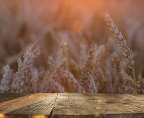 Wall Mural - wood board table in front of field of wheat on sunset light. Ready for product display montages