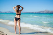 © fischers - Young woman in bikini with her hand over head enjoying hot summer day on the beautiful Playa de Muro beach, Mallorca, Spain