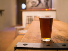 Glass Of Beer On Wooden Table In Pub Background