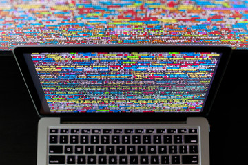 Laptop screen with source code in front of the bigger display