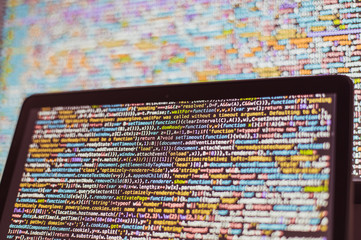laptop screen with source code in front of the bigger display