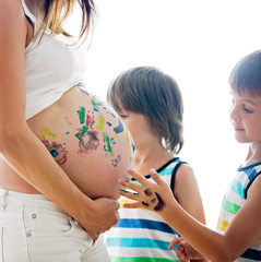 Happy children, boys, painting on mommy's pregnant belly