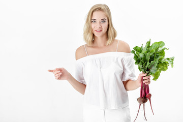 Wall Mural - Beautiful blond woman holds beetroot with green leaves on white background. Health and vitamins