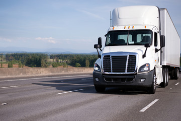 White semi truck with high roof day cab and semi trailer move on interstate multi-lines highway