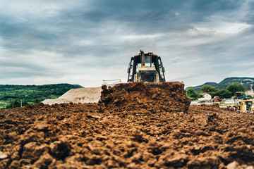 Wall Mural - mini bulldozer moving dirt and earth with scoop. Industrial details of landscaping