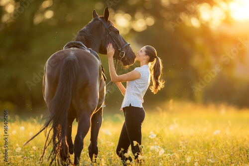 Photographie Young woman with her horse in evening sunset light