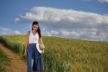 Poster - Woman is walking along the road among the fields and a typical Tuscan landscape behind her. Tuscany, Italy