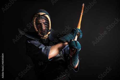 Zdjęcie XXL Człowiek ćwiczy sztuki walki kendo w tradycyjnej zbroi. Huśta się shinai mieczem bambusowym.