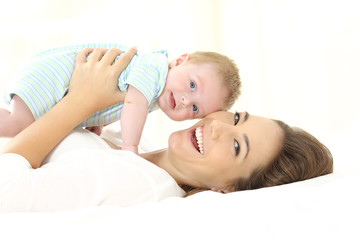 Wall Mural - Mother and baby looking at camera on a bed